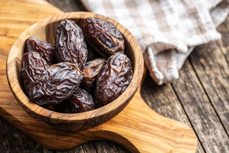 Dried dates fruit in wooden bowl on wooden table.の写真素材