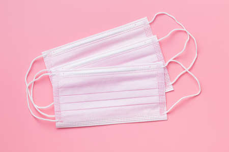 Corona virus protection. Pink medical paper face masks on pink background.