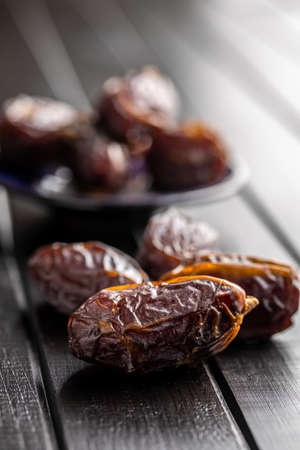 Dried dates fruit on black wooden table.