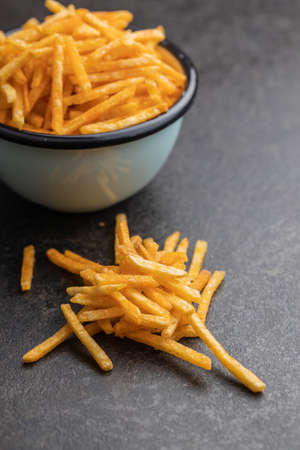 French fries. Fried mini potato sticks on black table.