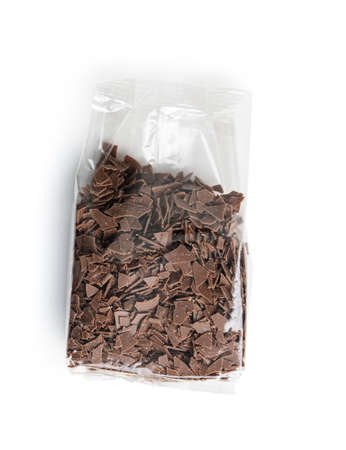 Grated dark chocolate in plastic bag. Chocolate flakes isolated on a white background.