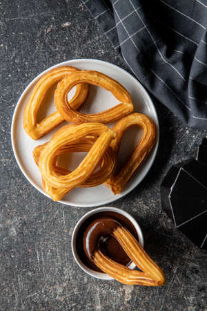 Tasty fried churros with chocolate dip on black table. Top view.の写真素材