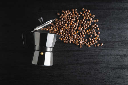 Coffee beans and bialetti coffee maker. Moka pot on black table. Top view.の写真素材