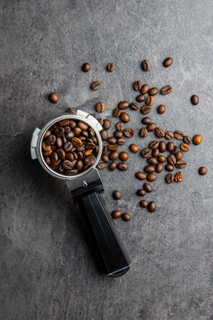 Roasted coffee beans in coffee filter holder on black table. Top view.の写真素材