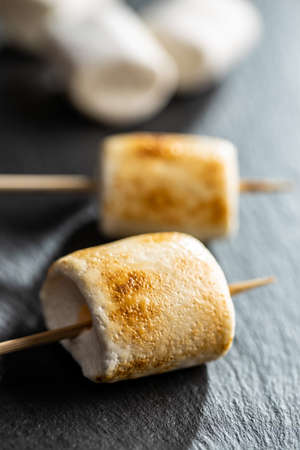 Grilled sweet marshmallows on a black table.の写真素材