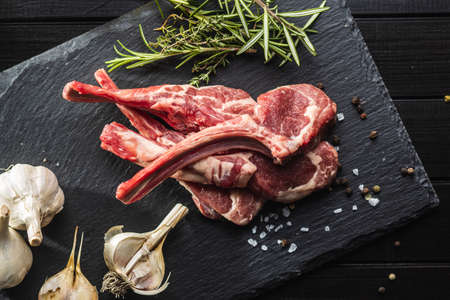 Slices raw lamb chops on black table. Top view.