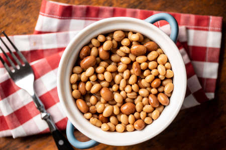 Mix of legume beans and chickpeas with sauce in a pot. Top view.
