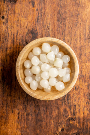 Pickled mini baby onions in wooden bowl. Top view.の写真素材