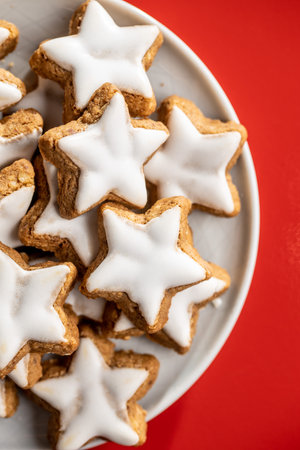 Icing gingerbread stars. Traditional Christmas cookies on red background. Top view.の写真素材