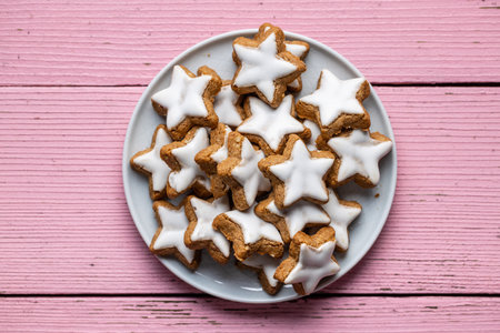 Icing gingerbread stars on plate. Traditional Christmas cookies on pink wooden table. Top view.の写真素材