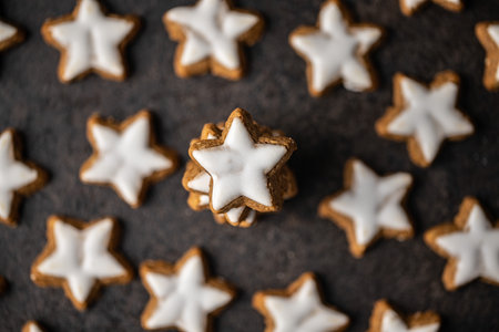 Icing gingerbread stars. Traditional Christmas cookies on black table. Top view.