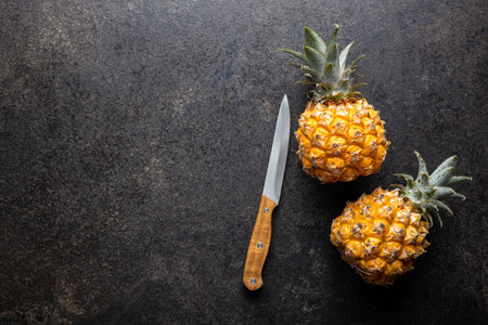 Ripe baby pineapple. Mini pineapple on black table. Top view.