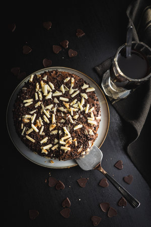 Sweet chocolate pie. Cake with chocolate sprinkles on black table. Top view.