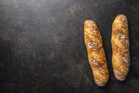 Crispy fresh baguettes on black table. Top view.
