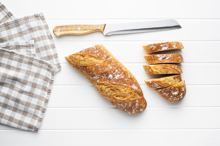 Crispy fresh baguettes. Sliced baguette on white table. Top view.