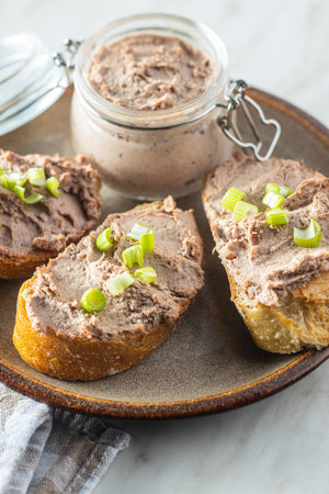 Liver pate on sliced baguette on plate.