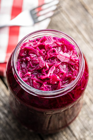 Red sauerkraut. Sour pickled cabbage in jar on wooden table.の写真素材