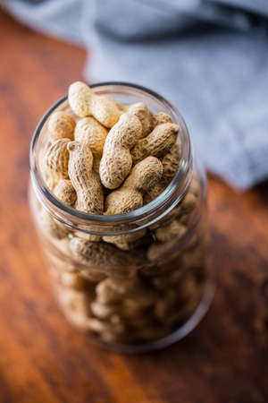 Roasted peanuts. Tasty groundnuts in jar on wooden table.の写真素材