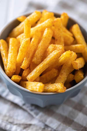 French fries. Salted snack. Potato chips in bowl on white table.