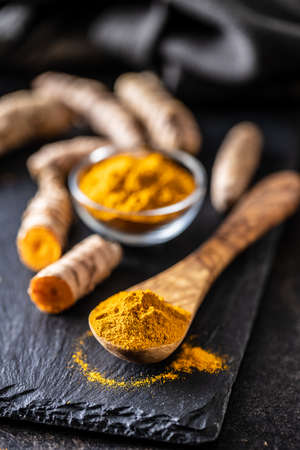 Indian turmeric powder and root. Turmeric spice. Ground turmeric in wooden spoon.の写真素材