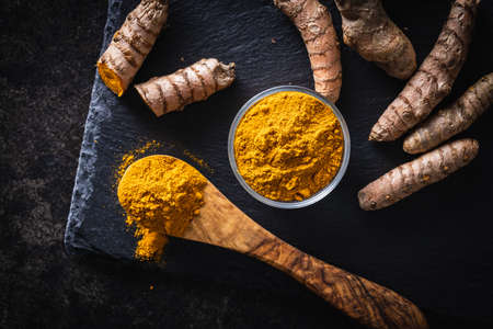 Indian turmeric powder and root. Turmeric spice. Ground turmeric in wooden spoon. Top view.の写真素材