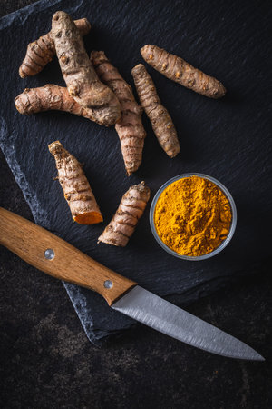Indian turmeric powder and root. Turmeric spice. Ground turmeric in bowl. Top view.の写真素材