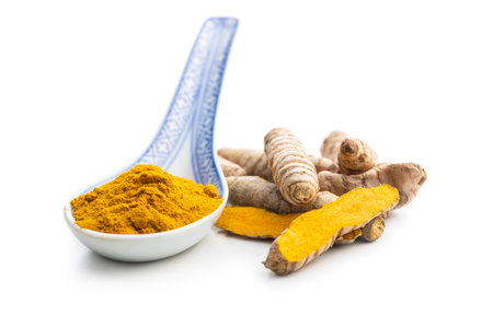 Indian turmeric powder and root. Turmeric spice. Ground turmeric isolated on white background.の写真素材