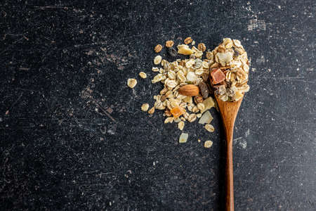 Beakfast cereals in wooden spoon. Healthy muesli with oat flakes, nuts and raisinsの写真素材
