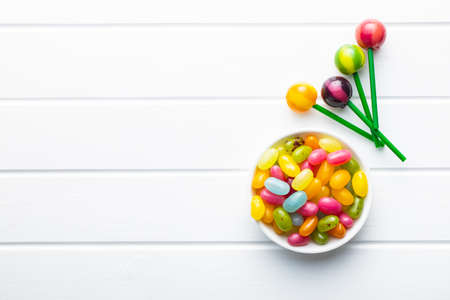 Sweet fruity lollipops and jelly beans on white table. Top view.の写真素材
