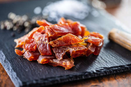 Dried chicken meat. Tasty jerky meat on cutting board.の写真素材