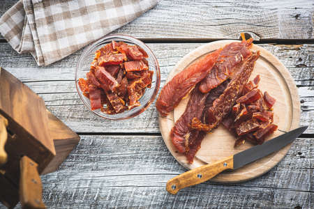 Dried chicken meat. Tasty jerky meat on wooden table. Top view.の写真素材