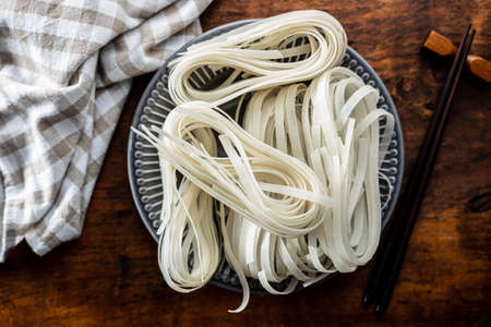 Dried white rice noodles. Raw pasta. Uncooked noodles on plate. Top view.