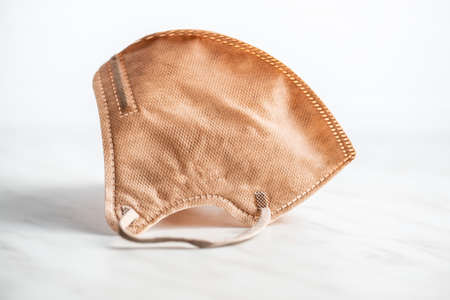 KN95 respirator mask for coronavirus protection. Brown face mask protects against   infection on white table.の写真素材