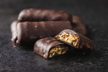 Chocolate bars with nuts filling on black table.の写真素材