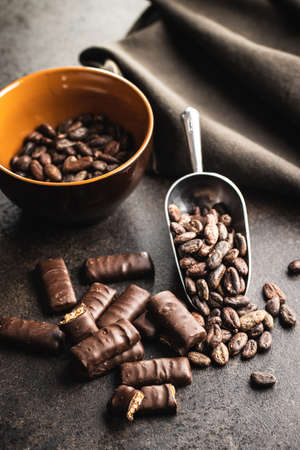 Chocolate bars with nuts filling and cocoa beans on black table.の写真素材
