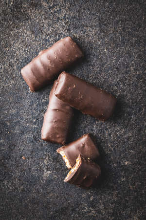 Chocolate bars with nuts filling on black table. Top view.
