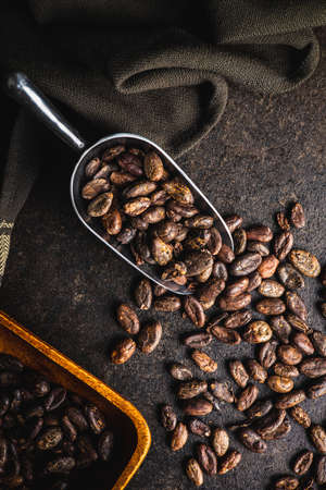 Roasted cocoa beans in scoop on black table. Top view.の写真素材