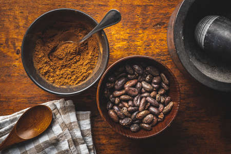 Roasted cocoa beans and cocoa powder in bowl on wooden table. Top view.の写真素材