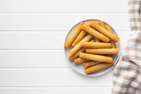 Sweet waffle tubes rolls on plate on white table. Top view.