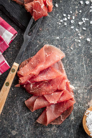 Sliced carpaccio. Raw beef meat on black table. Top view.の写真素材