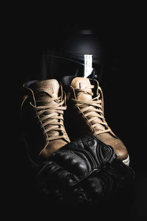 Safety motorcycle accessories. Leather gloves, helmet and shoes on black background.