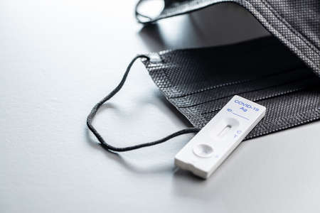 rapid antigen test. Rapid antibodies test kit and surgical face mask on gray background.