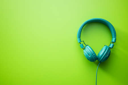 Green wired stereo headphones on green background. Top view.
