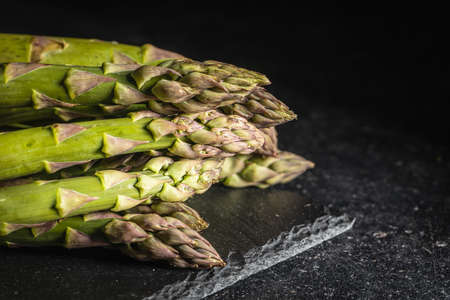 Fresh raw uncooked green asparagus on cuttting board.の写真素材