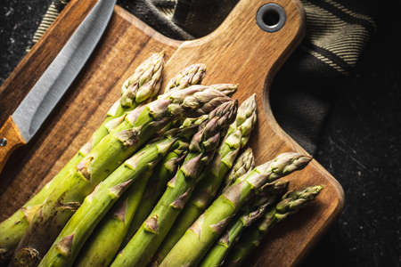Fresh raw uncooked green asparagus on cuttting board. Top view.の写真素材