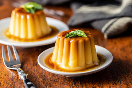 Sweet vanilla pudding. Sweet dessert with caramel topping on wooden table.