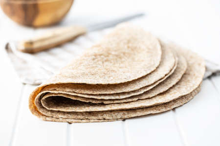 Whole grain tortilla wraps on white table.