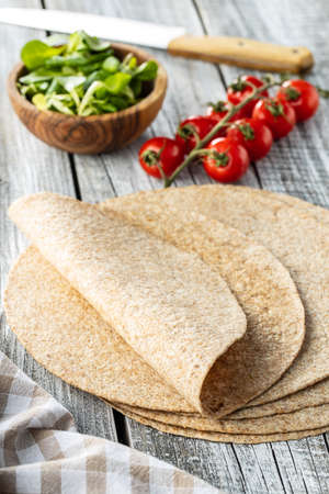 Whole grain tortilla wraps on wooden table.