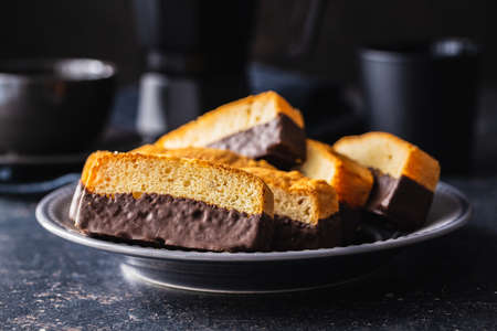 Sliced sponge dessert. Sweet sponge cake with chocolate on black table.