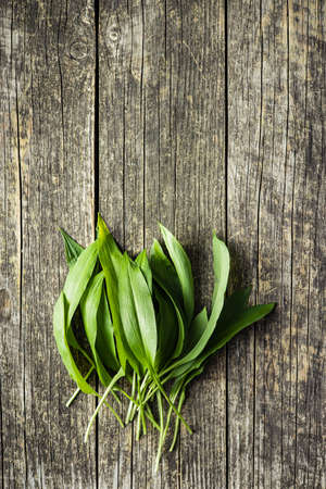 Green ramsons leaves. Wild garlic on old wooden table. Top view.